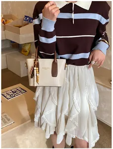Detail of cream leather bucket bag with brown handles and vintage wooden bead charm