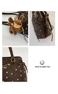 Detail of dark brown tote bag with star patterns, plush dog charm, and golden metal hardware
