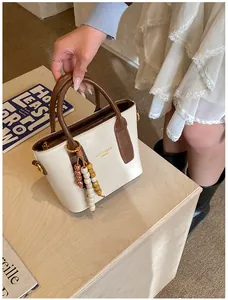 Detail of cream bucket bag with brown handles and a vintage colorful beaded keychain