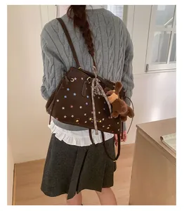 Detail of a brown canvas tote bag with star patterns and a plush bear charm on back