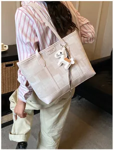 Dettaglio borsa tote in tela crema con cinturini in pelle e ciondolo a forma di cavallo