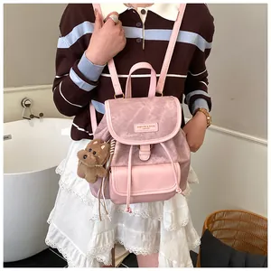 Detail of pink mini tote backpack with plush bear charm and metallic brand tag