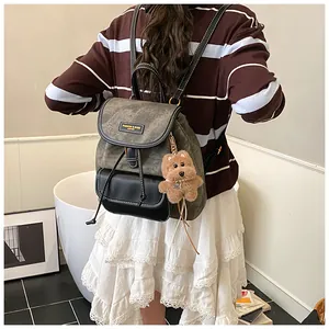 Detail of vintage canvas backpack with leather trim and cute plush bear accessory