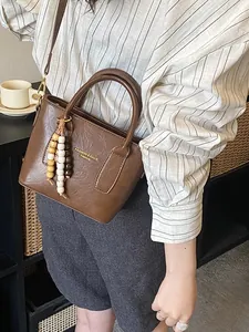 Brown retro bucket bag with round handles and bohemian beaded charm on a model