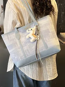 Borsa tote oversize azzurra con trama floreale e ciondolo a cavallo indossata da modella