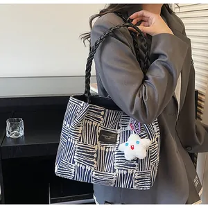 Detail of blue and white striped tote bag with woven handles and star plush pendant
