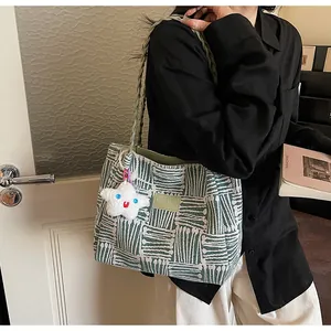 Detail of green and white geometric woven tote bag with star plush charm and rope handles