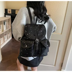 Detail of black backpack with white star pattern and buckle straps in a cozy room