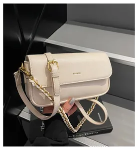 Detail of cream baguette bag with gold chain strap and 'NO FILTER' text on the flap