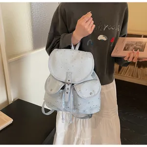 Close-up of light blue canvas backpack featuring silver star patterns and flap pockets