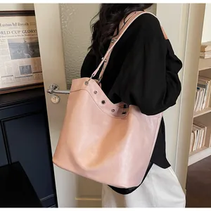 Detail view of large pink faux leather tote bag with metal eyelets and shoulder strap
