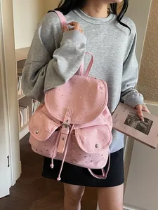 Pink canvas backpack with silver star patterns and flap pockets worn by a model