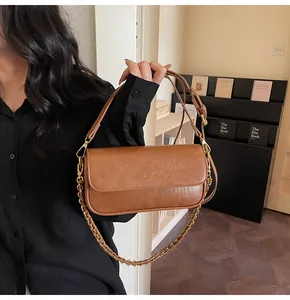 Detailed close-up of brown baguette bag with leather chain strap and logo hardware