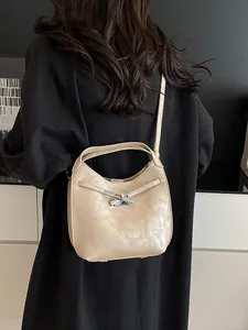 Chic beige leather bucket bag with silver metal buckle on a black trench coat