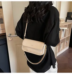 Detail of cream rectangular baguette bag with gold chain and No Filter logo on shoulder