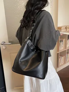Chic black large capacity tote bag with silver eyelet details worn by a model