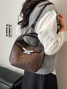 Dark brown vintage half-moon bucket bag with silver metal cross buckle shown on model