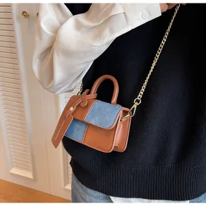 Detail of a brown faux leather and blue denim patchwork mini crossbody bag with gold chain