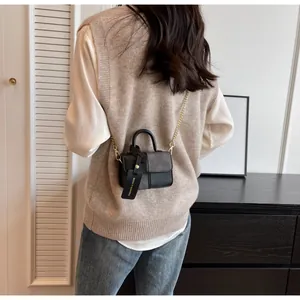 Rear view of a model wearing the black mini square bag with golden chain strap