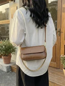 Vintage brown leather baguette bag with gold chain and crossbody strap shown on model