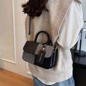 Minimalist black and grey crossbody bag with round handle and gold hardware on model