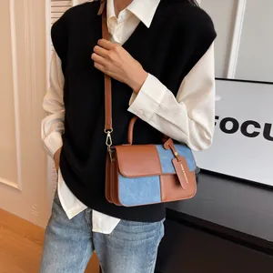 Chic brown leather and blue denim patchwork shoulder bag with fashion tag charm
