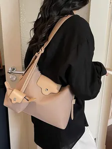 Minimalistische beige lederen draagtas met kleine portemonnee op een model in de studio