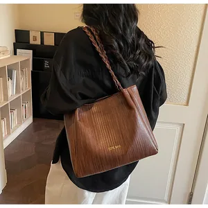 Détail du cabas tissé marron avec lettrage TOTE BAG doré et bandoulière tressée