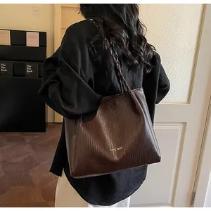 Gros plan d'un sac cabas marron foncé à texture tressée avec inscription dorée