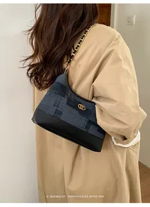 Détail du sac cabas vintage en denim patchwork avec chaîne dorée sur manteau minimaliste