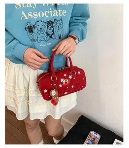 Detail view of red barrel bag featuring star pattern, rocking horse patch, and bear charm
