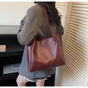 Détail du sac cabas bordeaux à texture tissée avec lettrage doré et anses tressées
