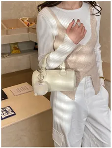 Dettaglio borsa Boston cilindrica bianco panna con ciondolo di peluche su una modella