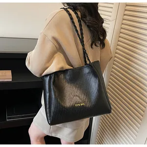 Détail de la texture tressée et lettrage TOTE BAG doré sur un grand sac à main noir