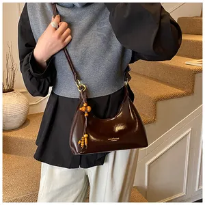 Detail view of dark brown oil wax leather baguette bag with beaded tassel charm