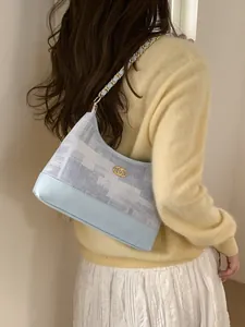 Sac fourre-tout bleu clair avec bandoulière chaîne dorée et logo métallique chic