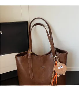 Vue détaillée du sac cabas marron en cuir PU avec bandoulière et pendentif en peluche