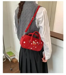 Detail of red crossbody baguette bag with white stars and a rocking horse embroidery
