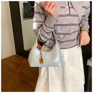 Detail of light blue patent leather hobo bag with decorative wooden bead tassel accent