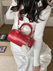 Elegante borsa Boston cilindrica rossa in pelle verniciata lucida con ciondolo in peluche