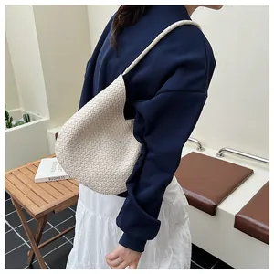 Detailansicht der beige gewebten Beuteltasche mit feiner Textur und Schultergurt