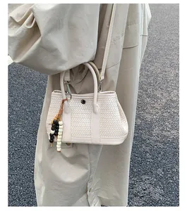 Detail van beige geweven crossbodytas met houten kralenhanger in een straatomgeving