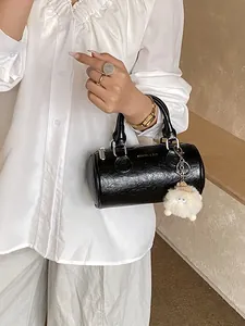 Elegante borsa a cilindro nera lucida con ciondolo di peluche indossata da modella