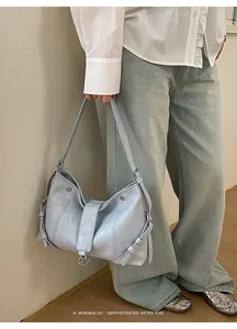 Gros plan du sac rétro bleu clair minimaliste porté avec une chemise et un jean bleu