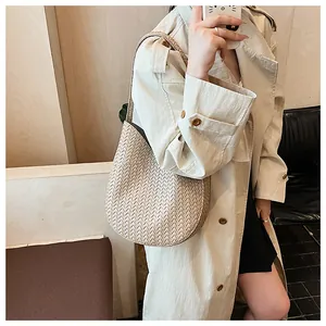 Detail der beige geflochtenen Eimertasche mit feiner Lederstruktur und Riemen