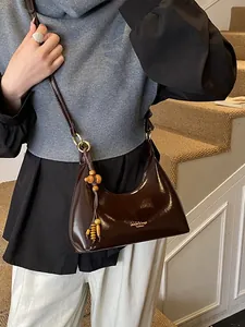 Dark brown patent leather dumpling crossbody bag with chic wooden bead tassel and gold hardware