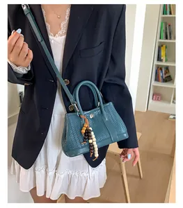 Detail van donkergroene geweven crossbodytas met houten kralen op een handtas