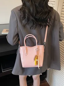 Minimalistische rosa Beuteltasche mit Perlenanhänger als Umhängetasche an einem Model