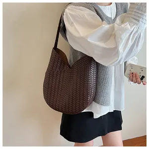 Detail der dunkelbraunen geflochtenen Lederstruktur einer minimalistischen Beuteltasche