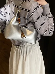 Metallic silver hobo bag with wooden bead charm and sleek shoulder strap styling
